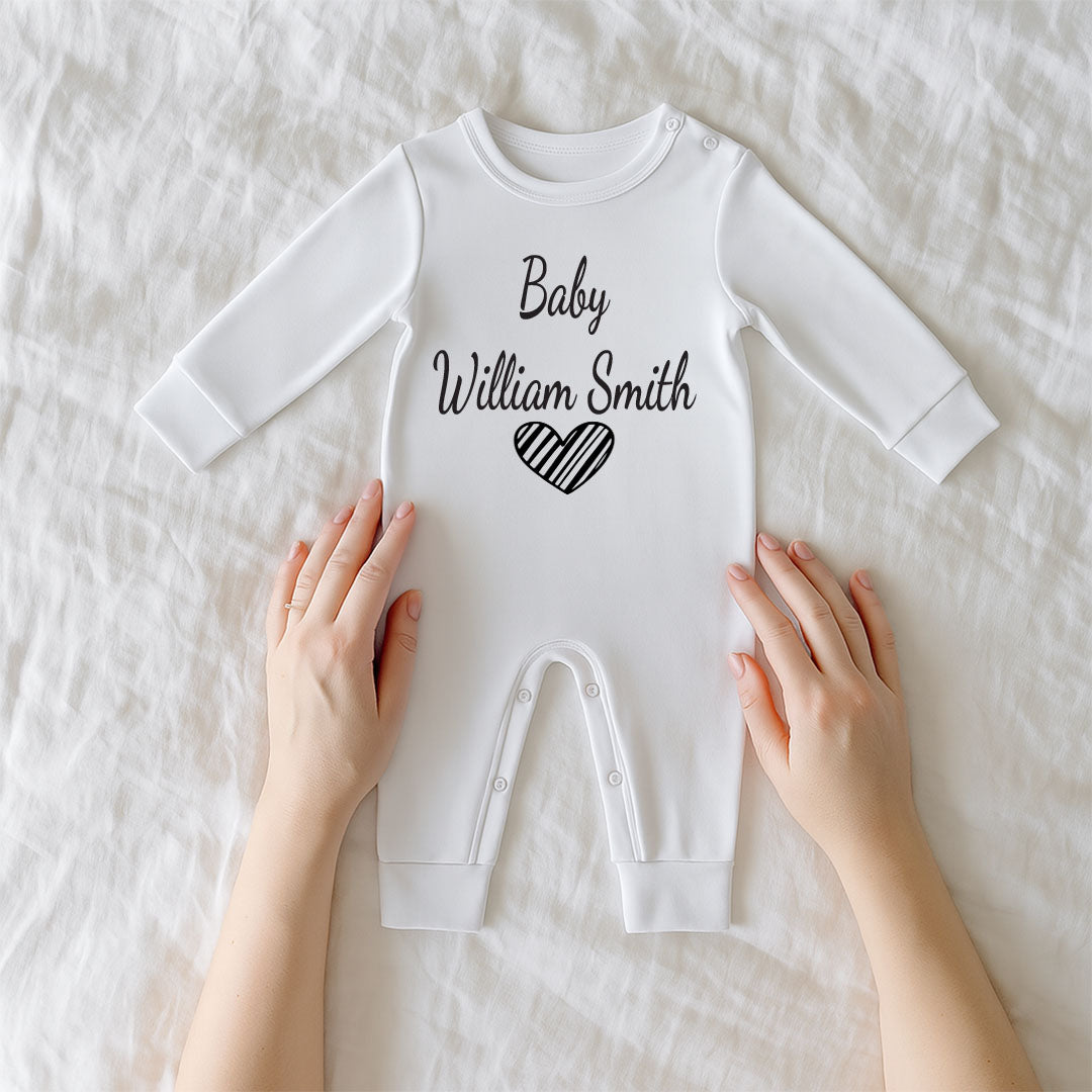 White baby onesie with 'Baby William Smith' printed on it, held by two hands on a white background.