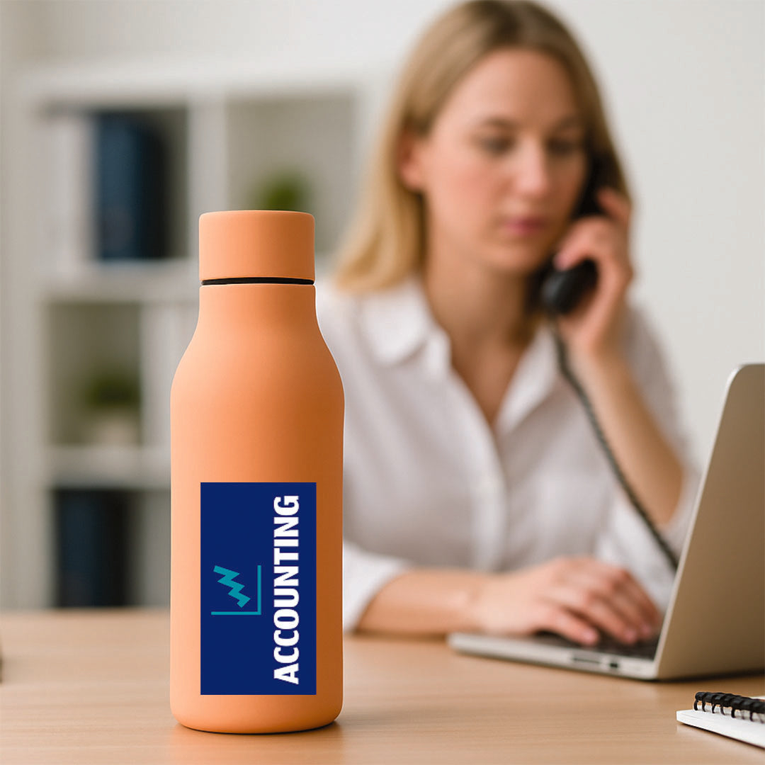 Pink water bottle with 'ACCOUNTING' label on a desk with a blurred background of a person using a laptop.