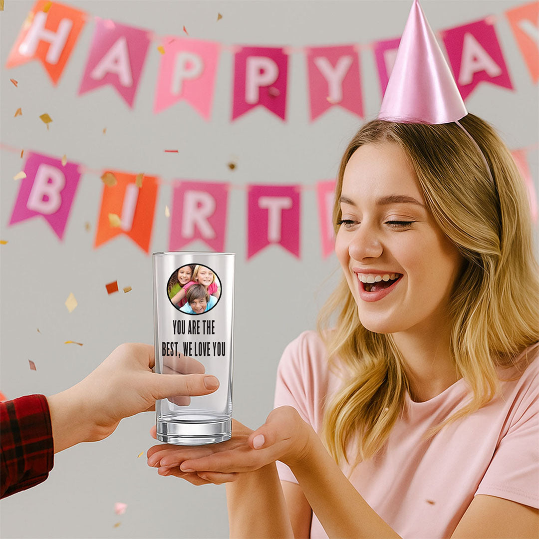 A woman receives a personalised clear glass with a circular family photo and "You are the best, we love you" text at a birthday party. Perfect for special occasions, memorable custom glass gift.