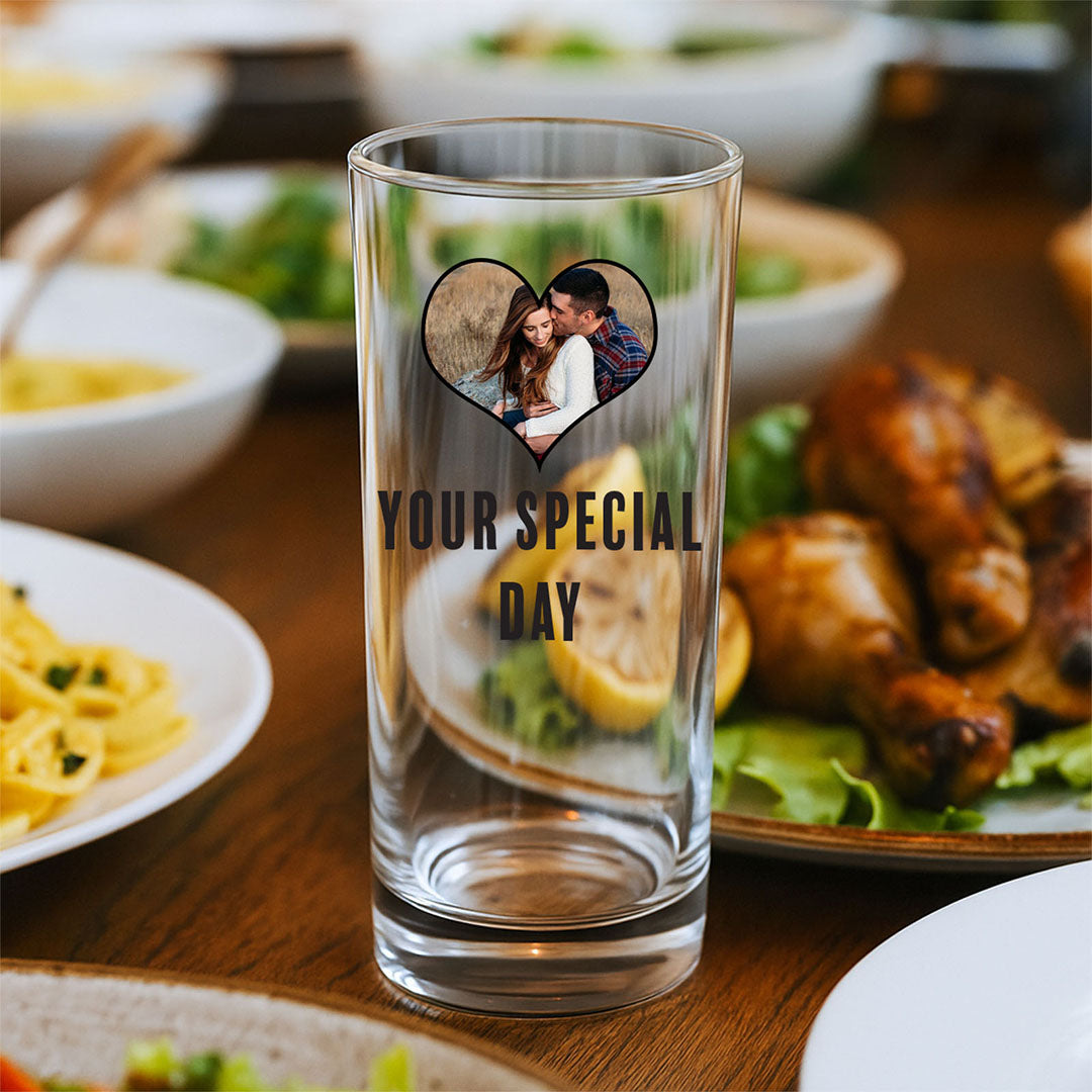 Personalised glass with a heart-shaped couple photo and "Your Special Day" text, displayed on a dinner table surrounded by delicious food. Great for anniversaries, weddings, and romantic occasions.