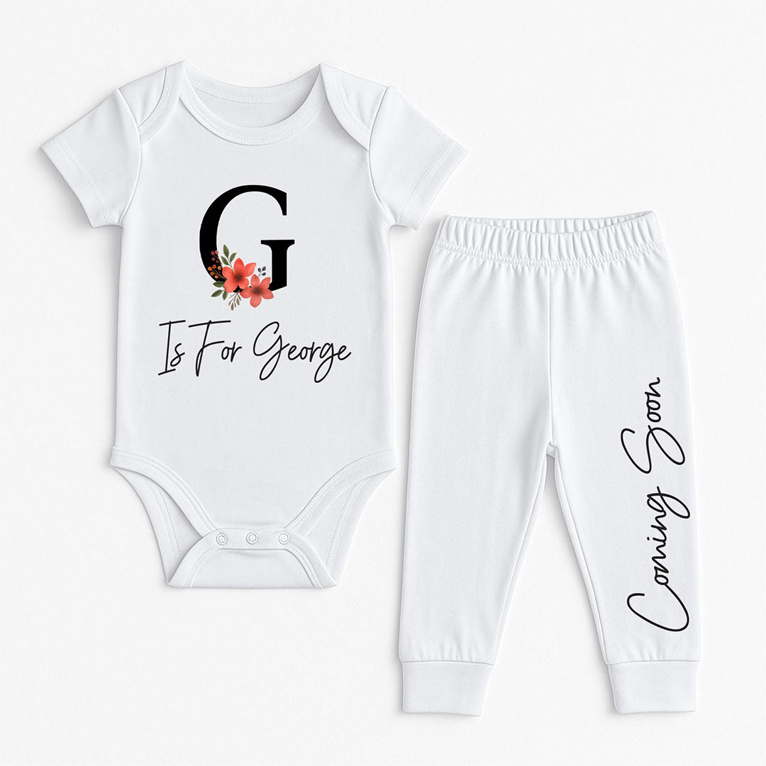 Adorable baby clothes set with personalized “G is for George” floral onesie and white pants featuring “Coming Soon” script – ideal for baby announcements.