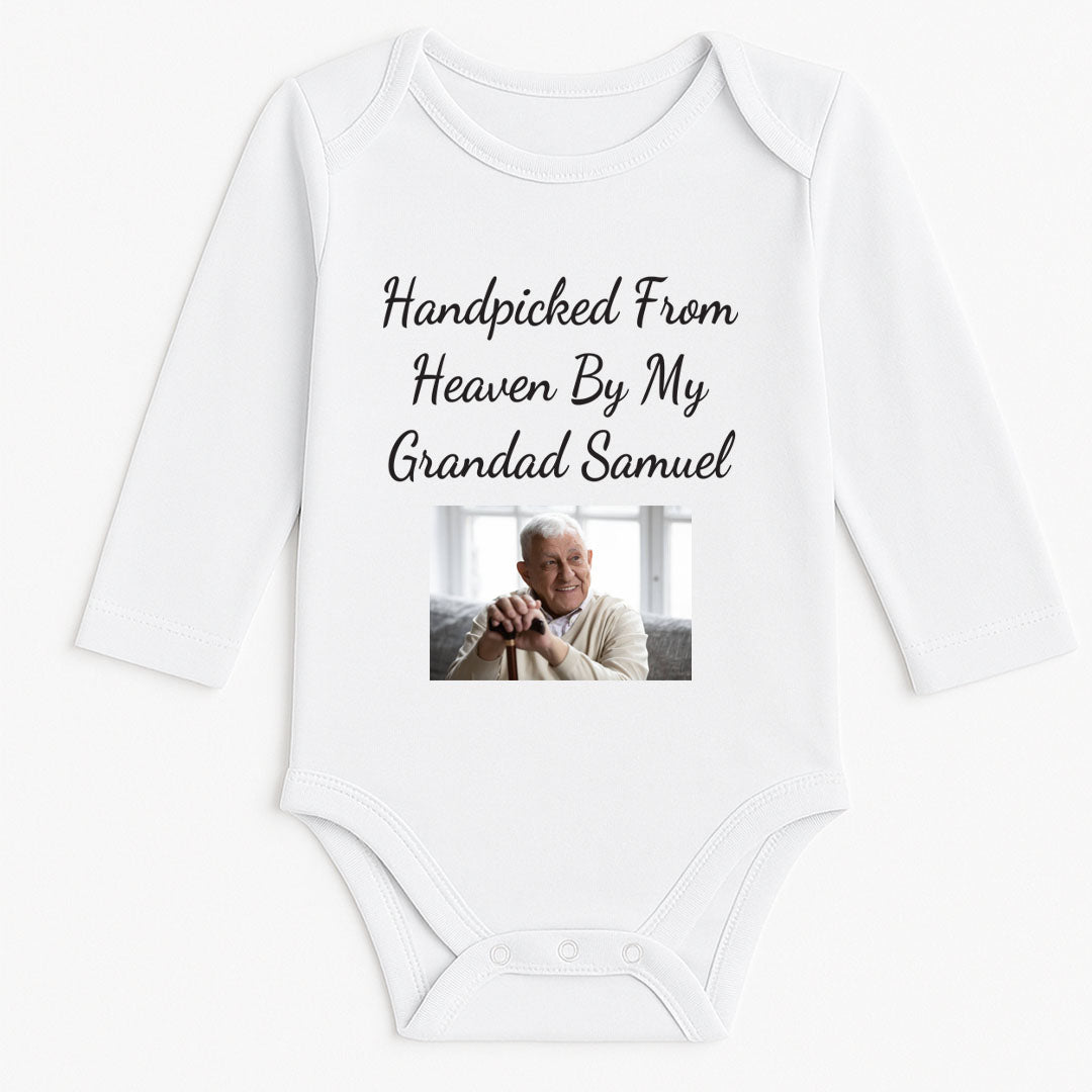 A white baby onesie with long sleeves, printed with the heartfelt message "Handpicked From Heaven By My Grandad Samuel" in elegant cursive, accompanied by a photo of a smiling elderly man in a cozy sweater. This design is perfect for memorial or sentimental gifts for babies, offering comfort and a personal touch.