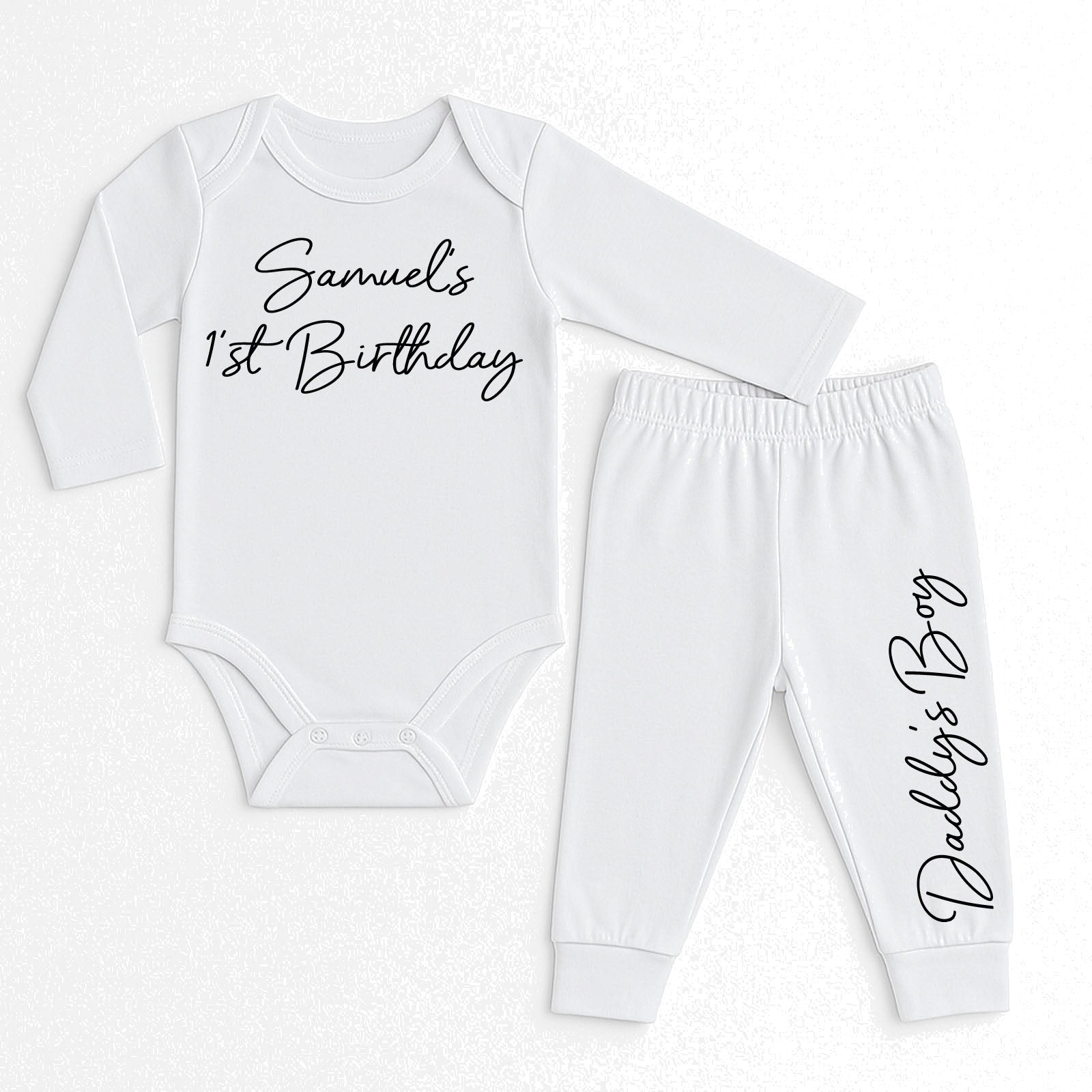 A two-piece baby clothing set consisting of a long-sleeve white bodysuit and matching jogger pants, both printed with black cursive text. The bodysuit reads 'Samuel's 1st Birthday' and the pants read 'Daddy's Boy'.