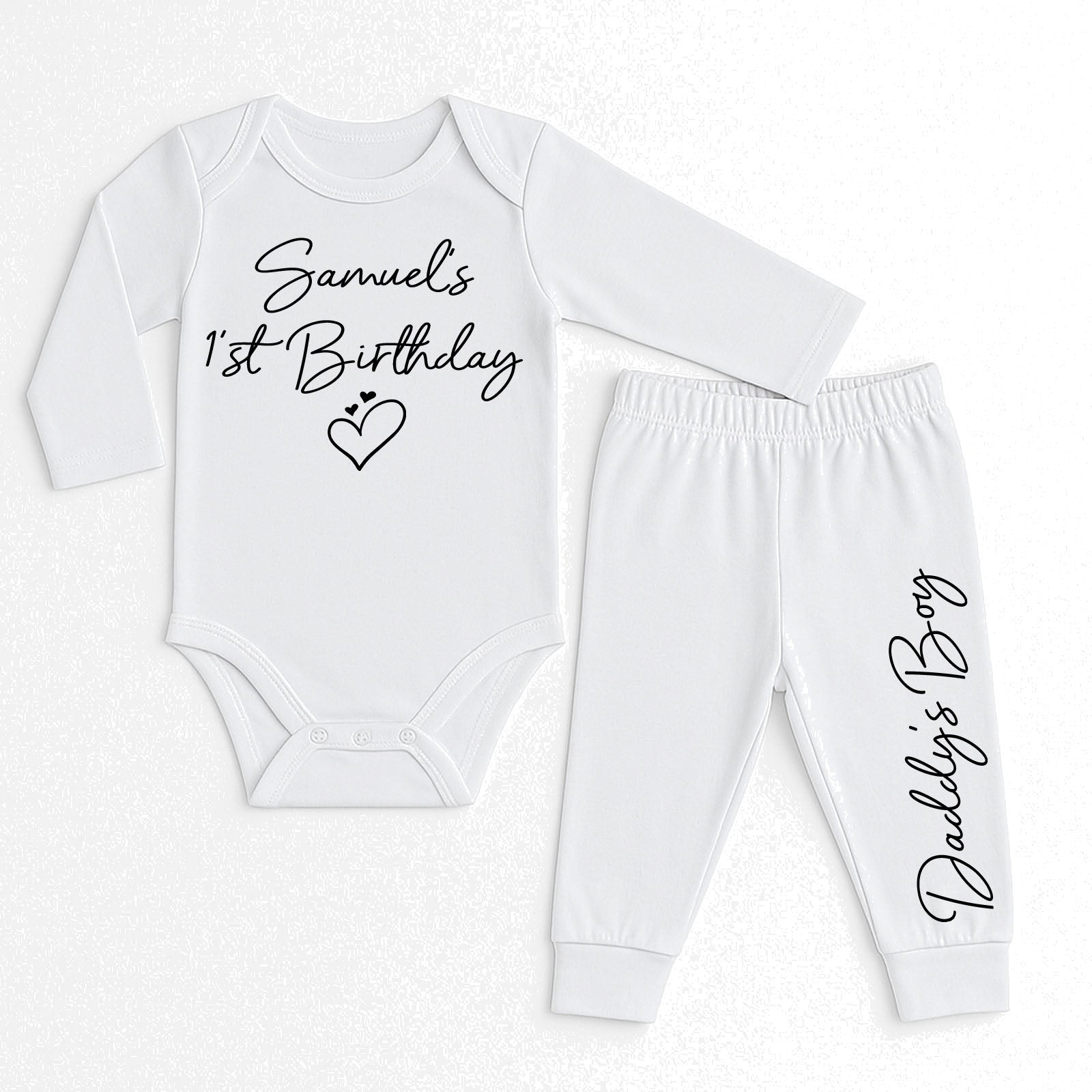 A two-piece baby outfit set consisting of a long-sleeve white bodysuit and matching jogger pants, both printed with black cursive text. The bodysuit reads 'Samuel's 1st Birthday' with a small heart, and the pants read 'Daddy's Boy'.