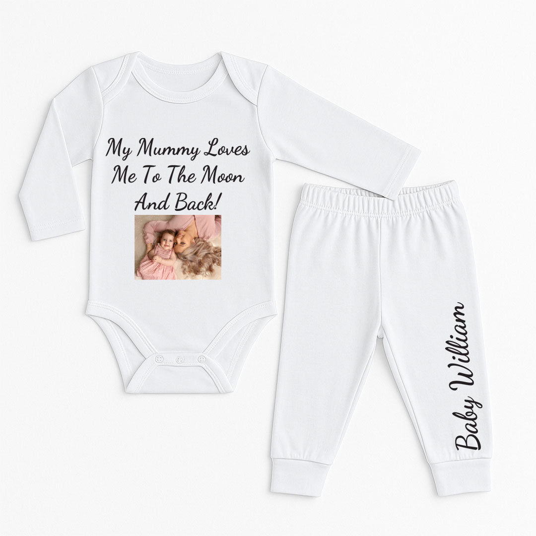 A baby onesie and pants set in white, with the message "My Mummy Loves Me To The Moon And Back" in elegant black script, complemented by a printed photo of a mother and daughter lying together on a pink blanket. The matching pants feature the child’s name, making this outfit a special and personalized gift for baby showers or birthdays.