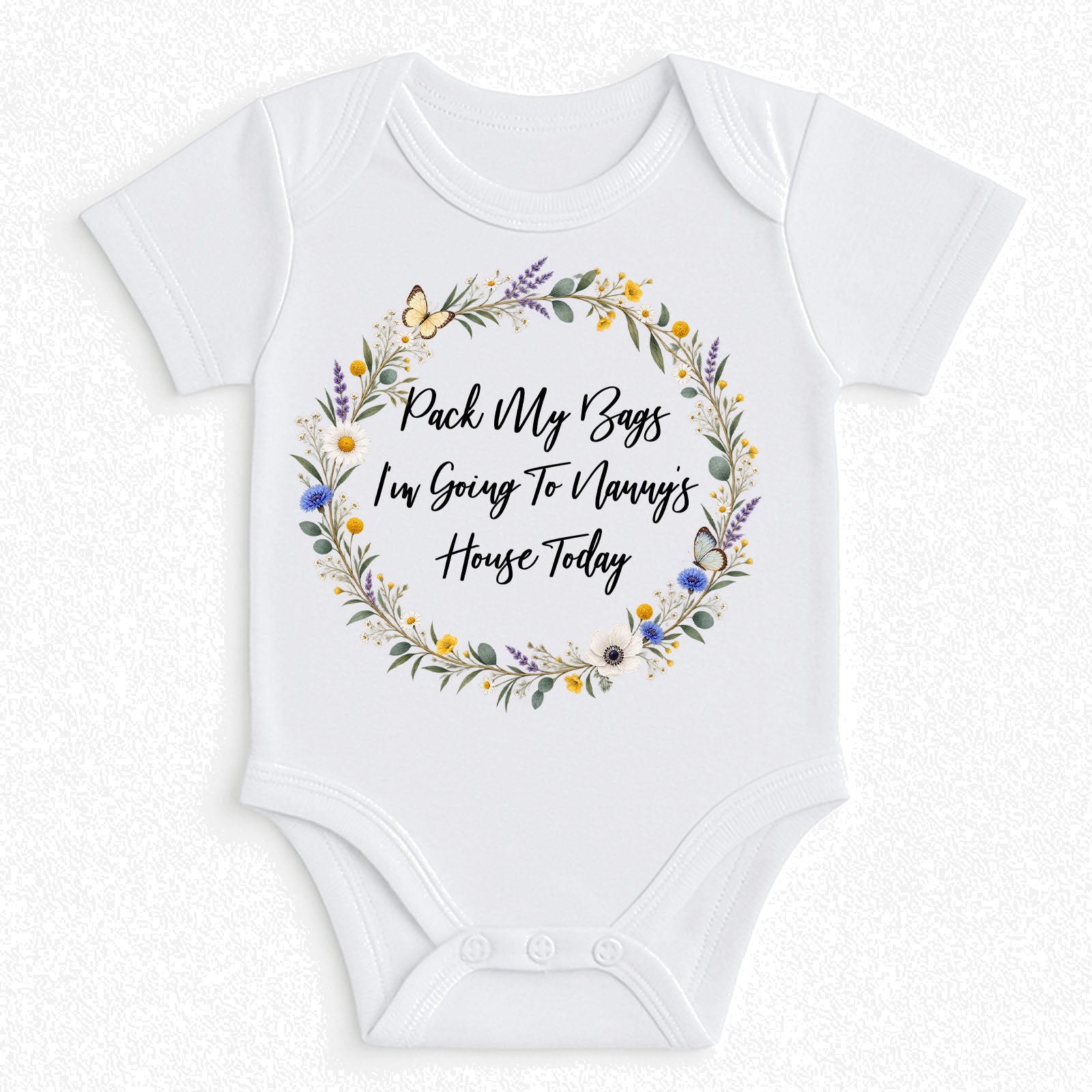 White short-sleeve baby bodysuit with a floral wreath graphic and the text 'Pack My Bags I'm Going To Manny's House Today' printed on the front, shown on a light textured background.
