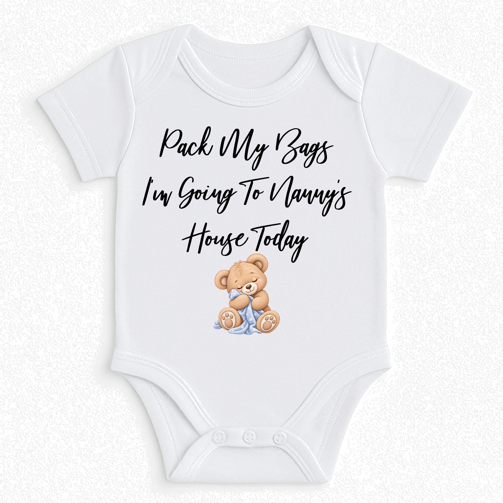 A white short-sleeve baby bodysuit with the text 'Pack My Bags I'm Going To Nanny's House Today' in black script, plus a small teddy bear illustration sitting in blue pants. The bodysuit is shown flat against a light textured background.