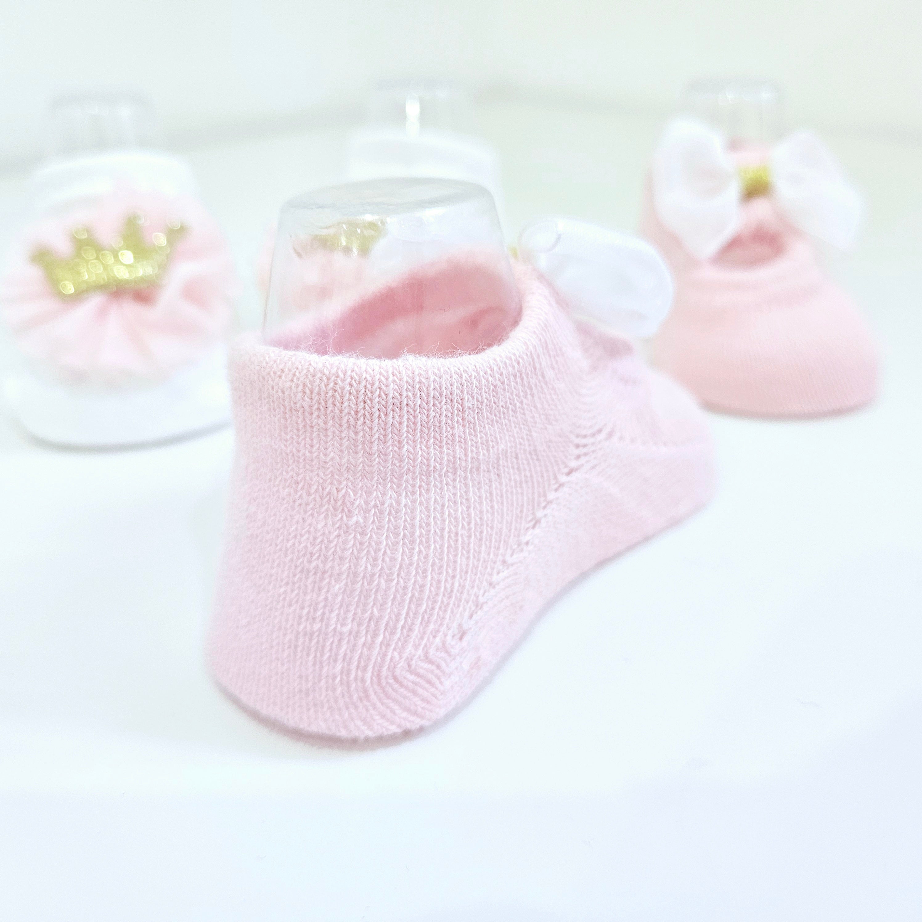 Cute and cozy baby socks for girls, featuring a two-pack set in soft pink and white, adorned with adorable bow and crown designs. Perfect for infants, newborns, and baby fashion.