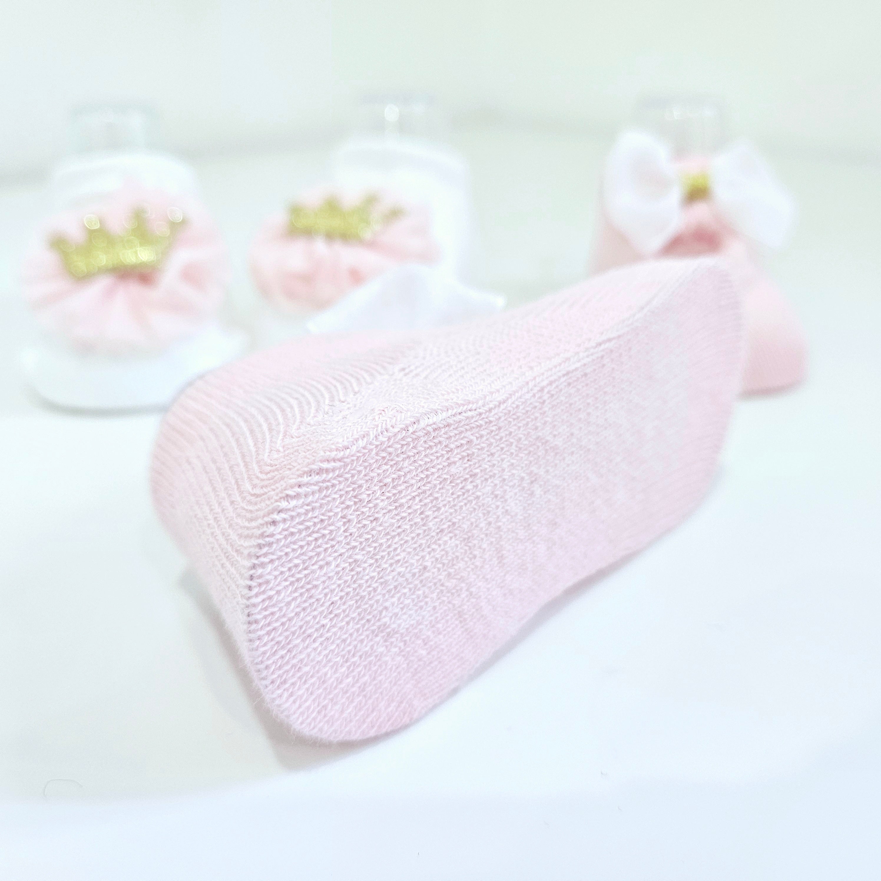 High-quality baby socks in white and pink for newborn girls, available in a two-pack with stylish crown and bow details. Soft, breathable, and perfect for baby outfits.