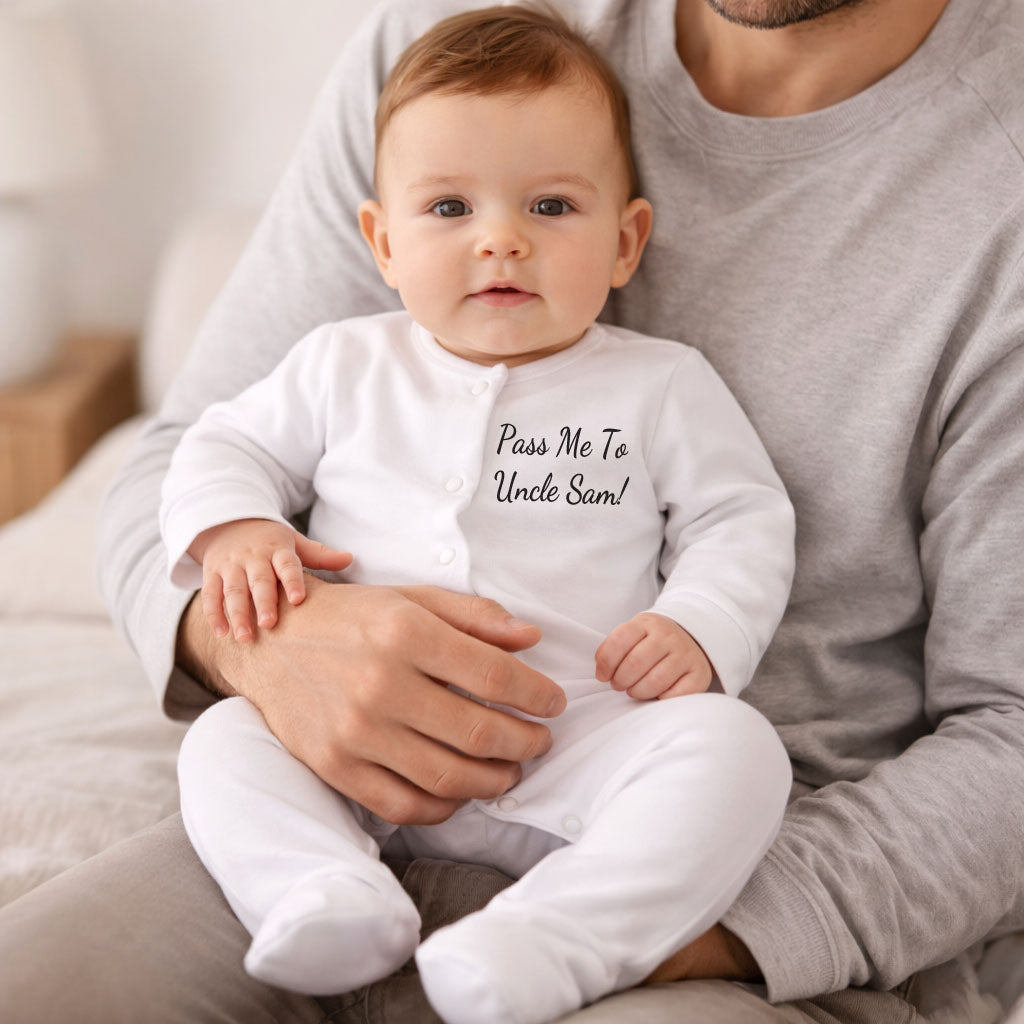 Baby in a white onesie with text sitting on a person's lap.